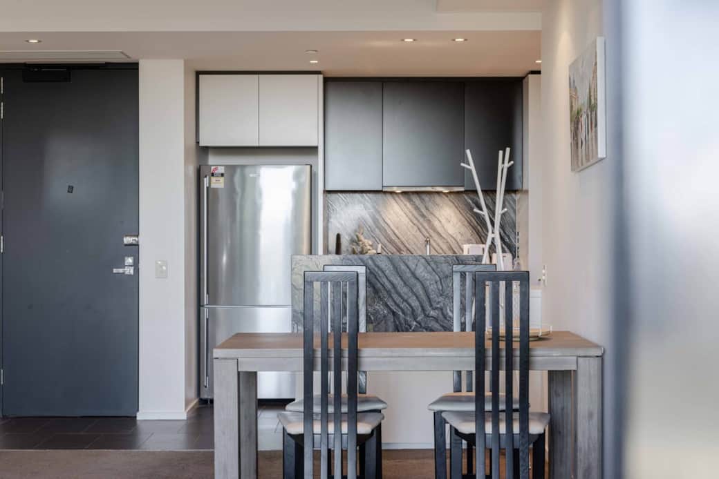 Step into our modern dining area, featuring a stylish table with four chairs. The area is equipped with stainless steel appliances and a sleek countertop. The design is both functional and inviting, perfect for cooking and enjoying a casual dining.