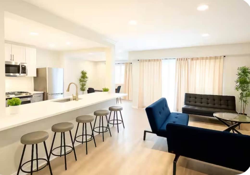 Spacious, modern living area with a 65” smart TV, three futon sofa beds, cozy fireplace, and a large balcony—perfect for relaxing. Openly connected to the kitchen and dining area for easy entertaining.