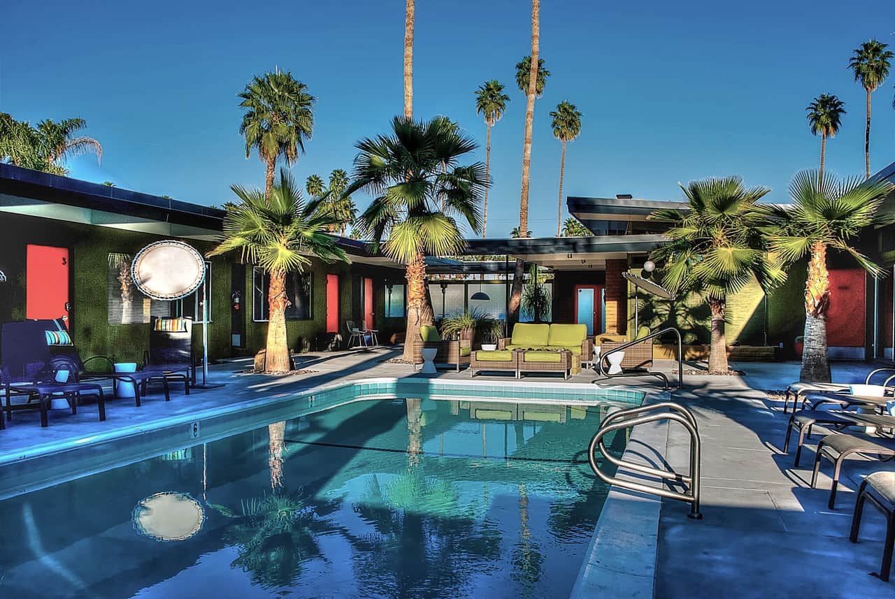 A pool area with palm trees, lounge chairs, and a building in the background.
