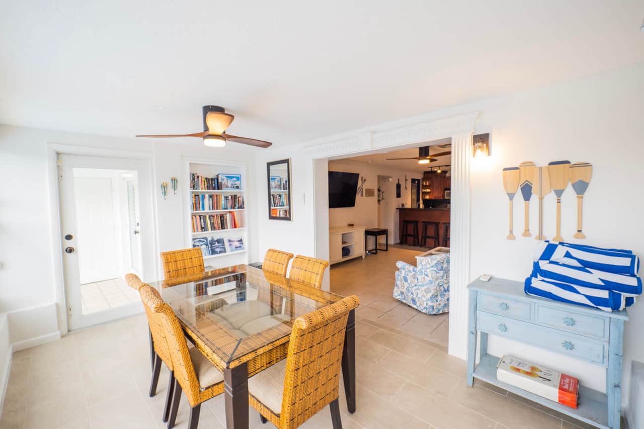The dining table seats six, steps from the open kitchen and the doors out to the pool deck.