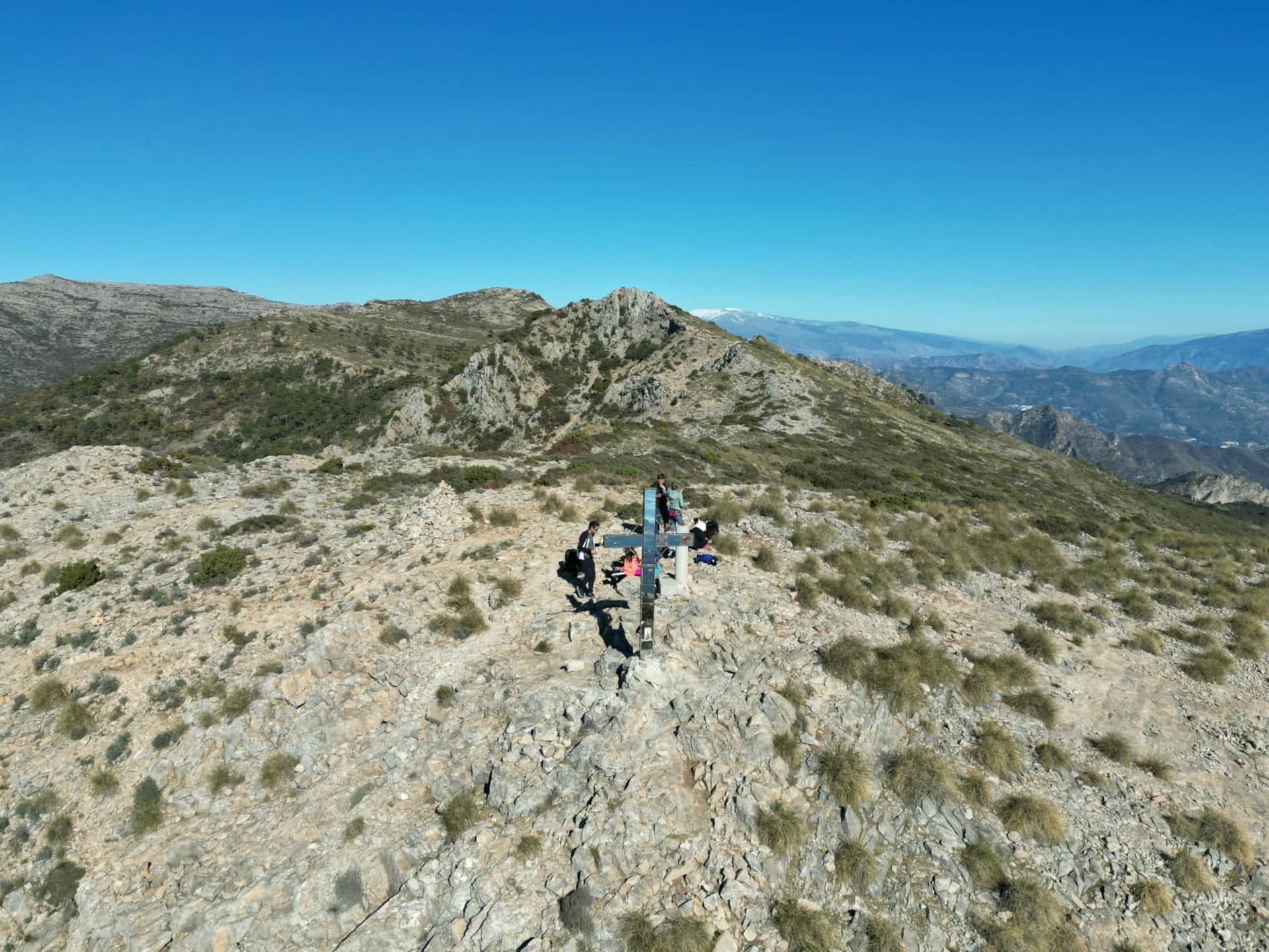 Summit cross on El Cielo mountain with panoramic views towards Sierra Nevada, Andalusia Spain