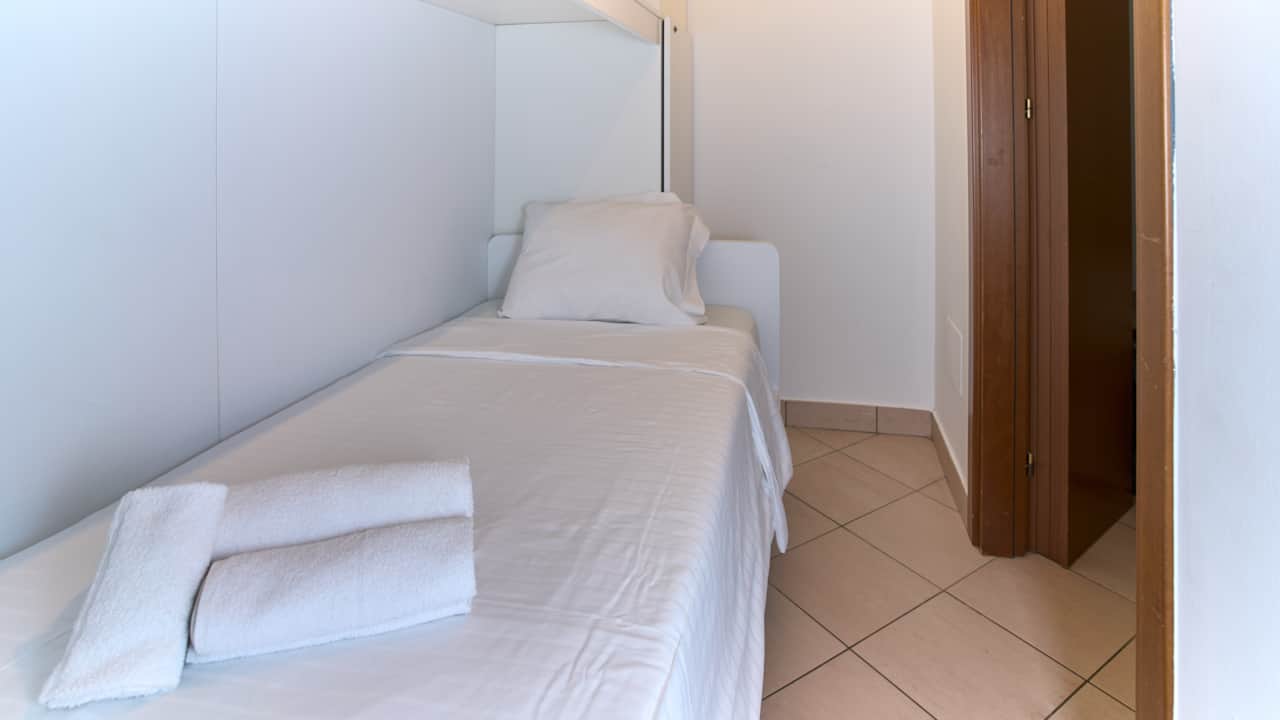 Bedroom with single bed, built-in wardrobe and terracotta floor