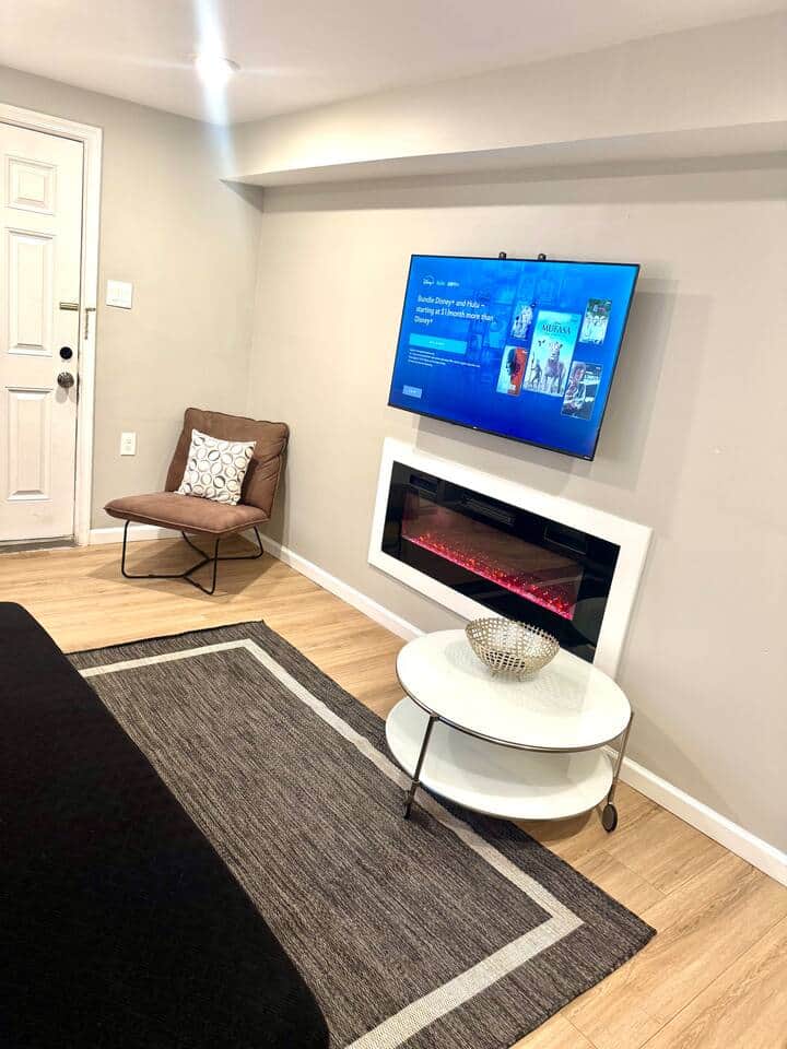Discover our elegantly designed living room, featuring two versatile futon sofa beds, a large flat-screen television, and a cozy fireplace, providing an ideal setting for both relaxation and social gatherings.