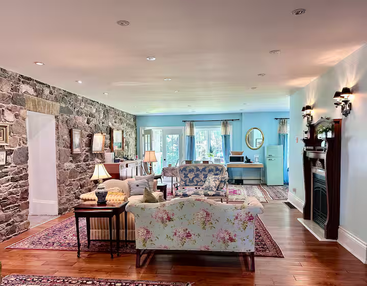 Elegant reception room with gas fireplace, seating areas, and 1830s stone wall by Scottish masons.
