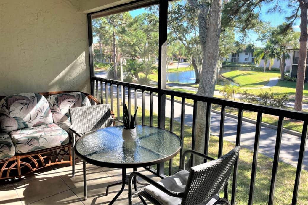 Enjoy your morning coffee on the screened lanai set up with a rattan sofa, table and chairs overlooking a peaceful pond with water fountain. 