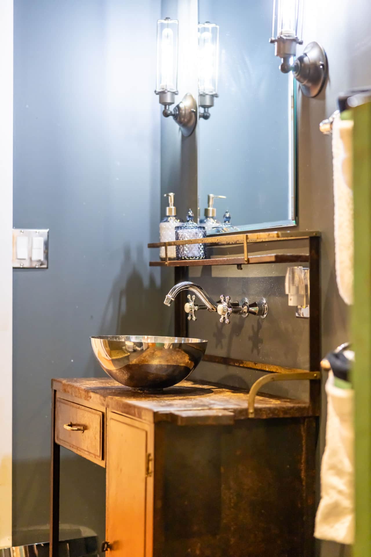 Brass basin and antique vanity in a deep green bathroom