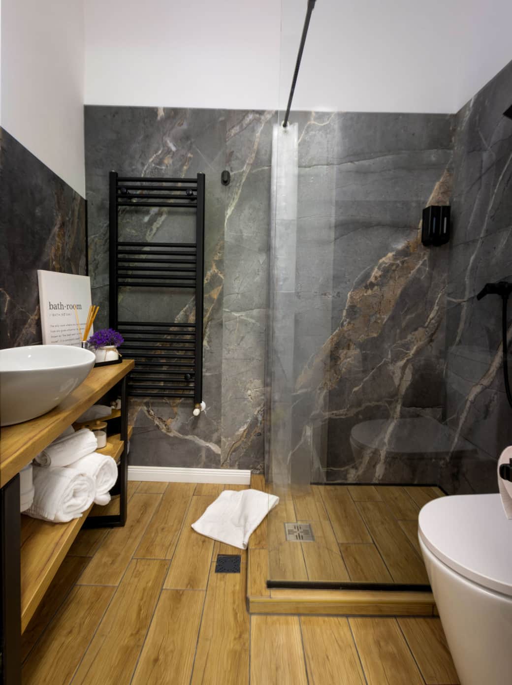 Luxury full bathroom with walk-in rain shower, marble accent wall, heated towel rack, vessel sink