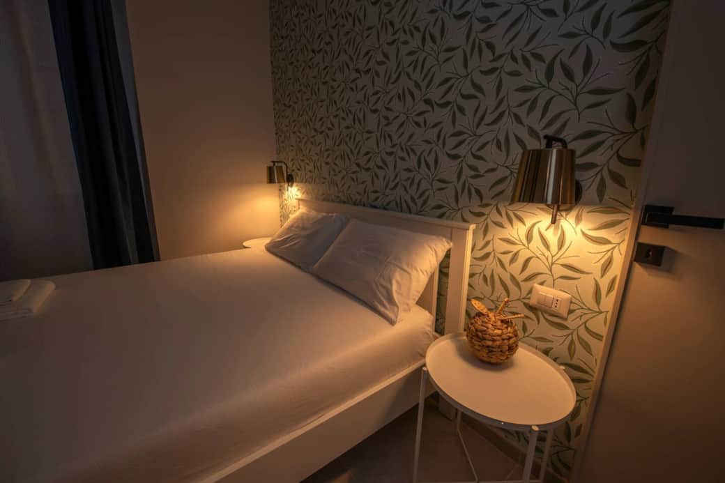 Dettagli camera a Civitavecchia: luci soft e comodini moderni per il relax di famiglie e gruppi.