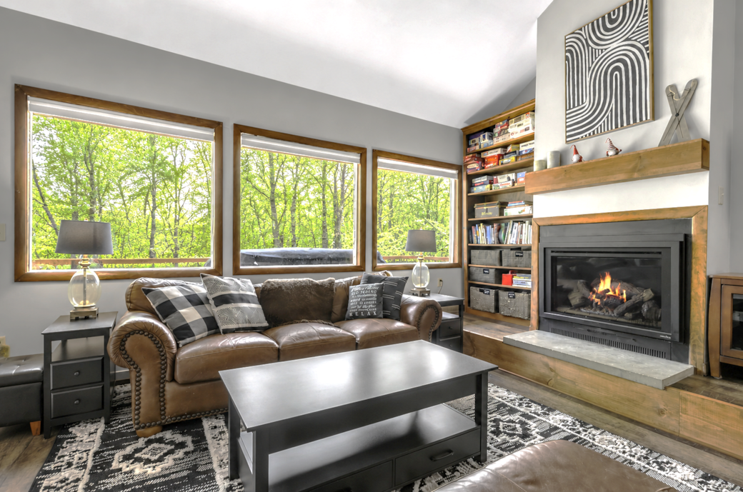 Bright living room with panoramic forest views, fireplace, games, and relaxing lodge feel Bright living room with panoramic forest views, fireplace, games, and relaxing lodge feel