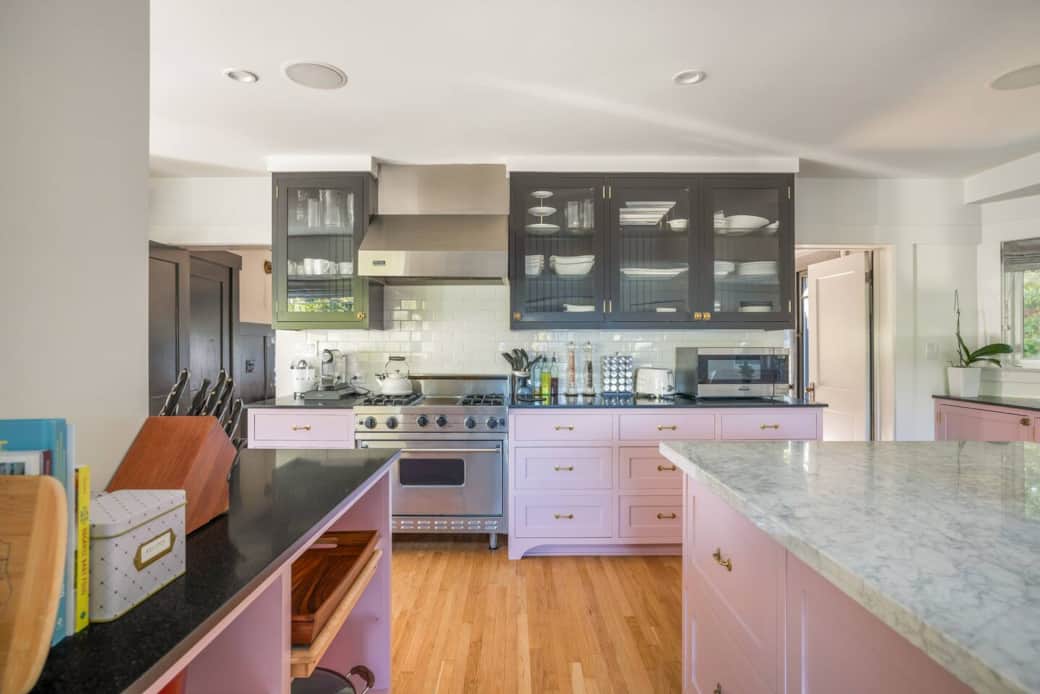 Modern kitchen with pink cabinets, stainless appliances, and full cookware—ready for your first meal
