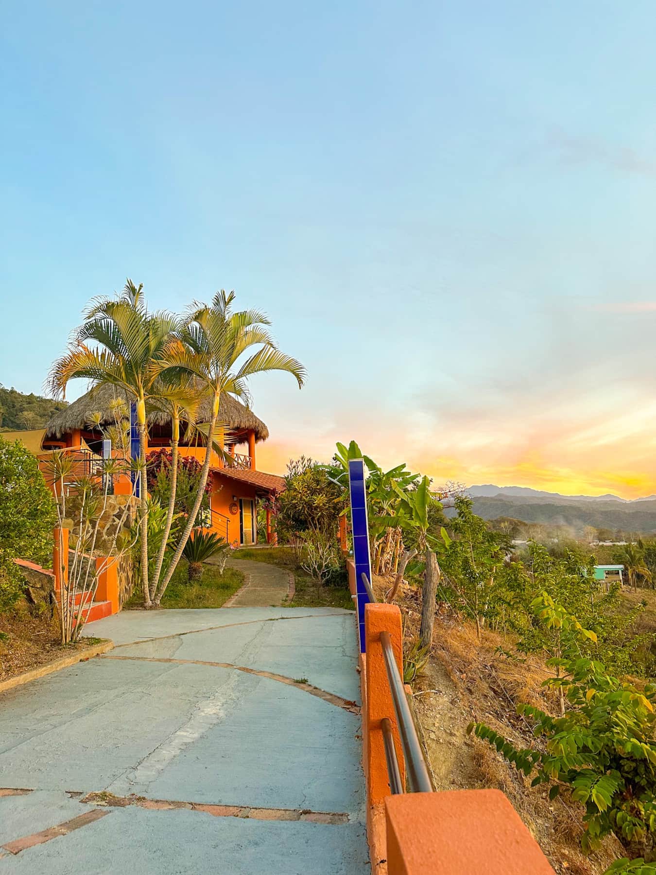 La Casa Redonda con su techo de palapa entre jardines al atardecer
