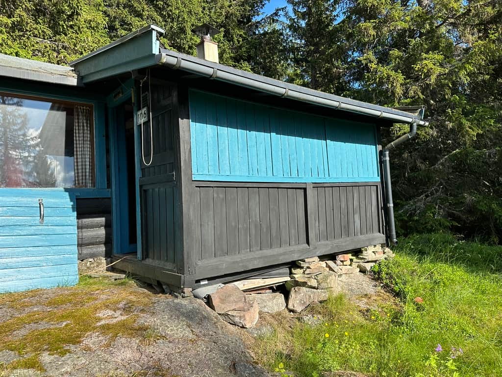 Lyseblå vindusrammer og tjærebeiset tømmer på Jøtulstua