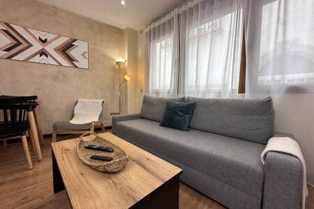 Salón con sofá cama, mesa baja y mucha luz natural