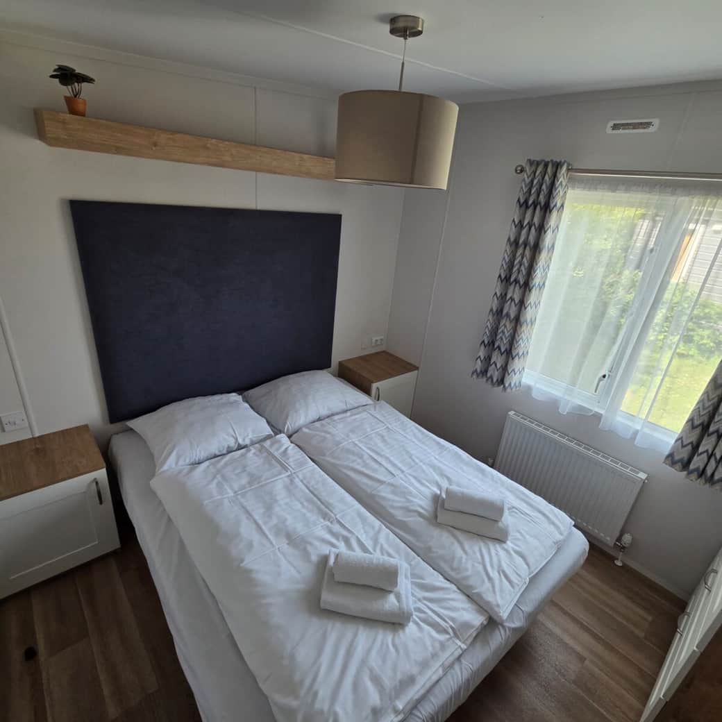 Freundliches Schlafzimmer mit gemütlichem Doppelbett, Nachttischen und natürlichem Tageslicht für einen entspannten Aufenthalt.