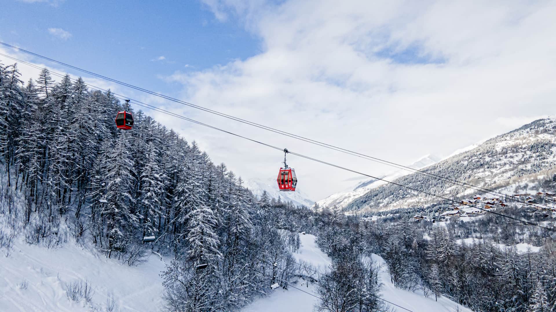 Télécabines rouges de Chantemerle au-dessus de la forêt enneigée, Serre Chevalier Vallée