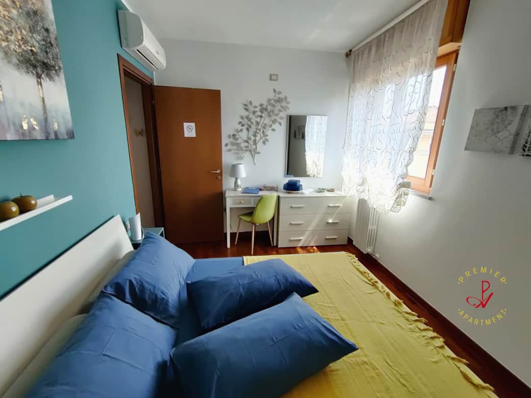 Dormitorio luminoso con escritorio, cómoda y ventana con vistas.
