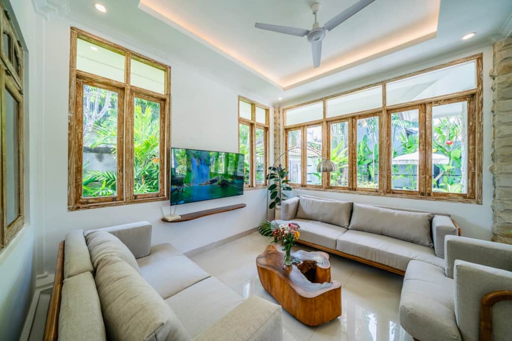 Bright, airy living room with plush seating and poolside garden views