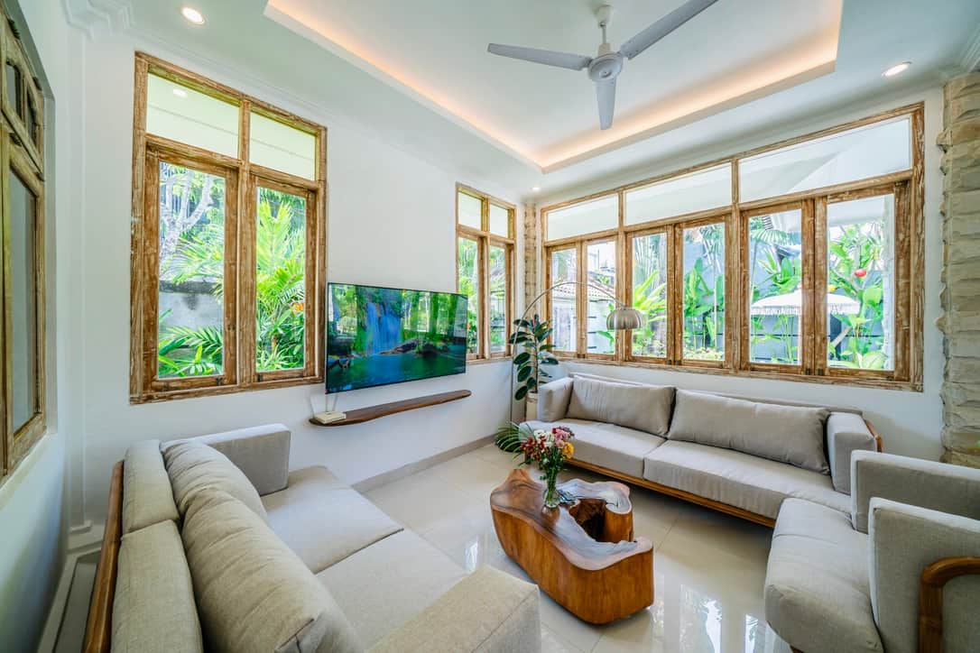 Bright, airy living room with plush seating and poolside garden views