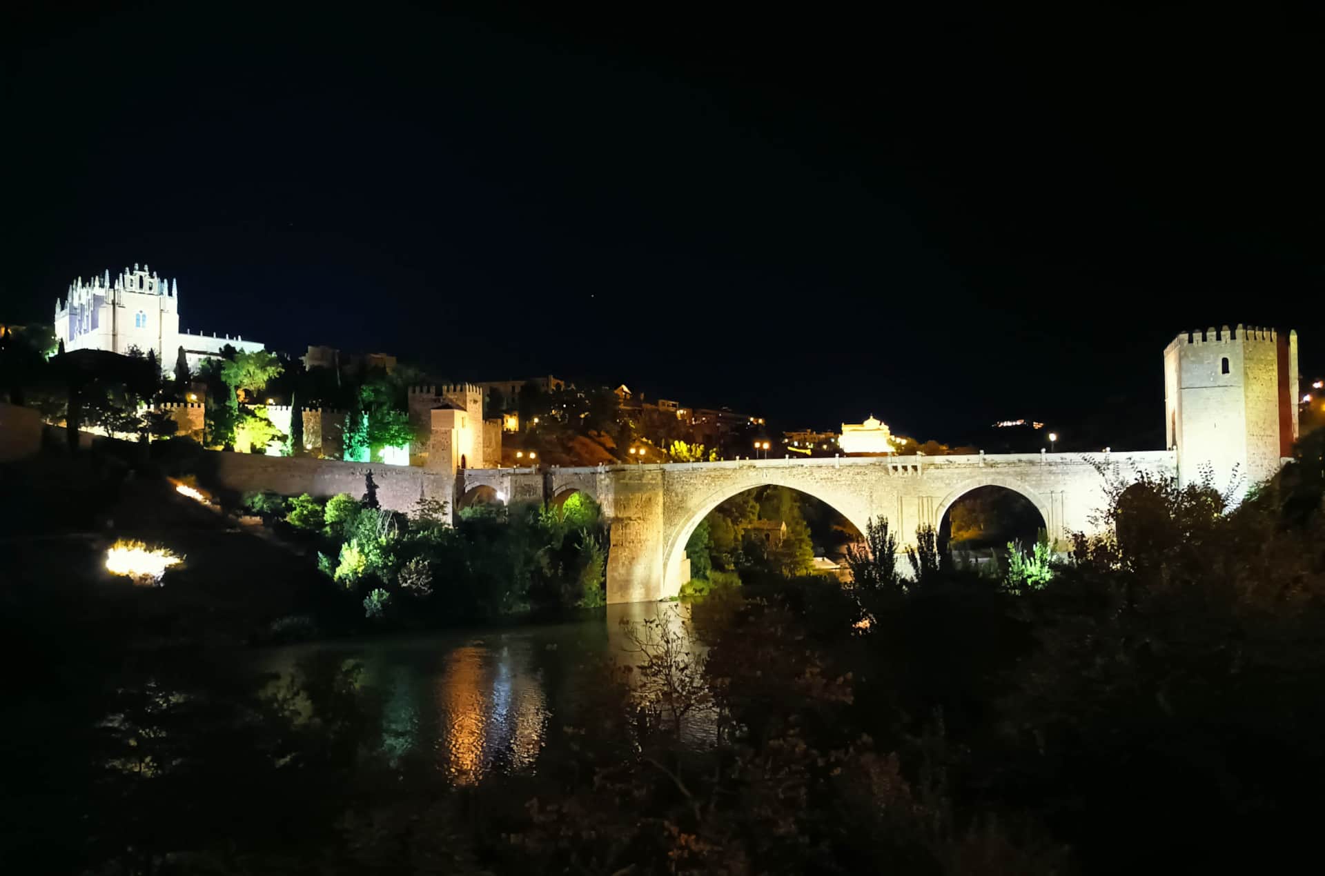 Casa rural cerca de Toledo - La Casita de Ale, ideal para visitar Puy du Fou Vista nocturna de puente medieval en Toledo con reflejos en el río y arquitectura iluminada