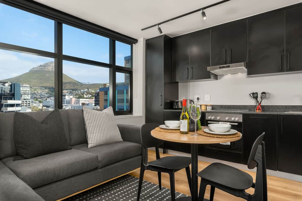 Views of Lions Head from the lounge- Dinning table with seating for 2, kitchen equipment, Nespresso coffee machine, basic supplies, toaster- open plan living with L-shaped couch.