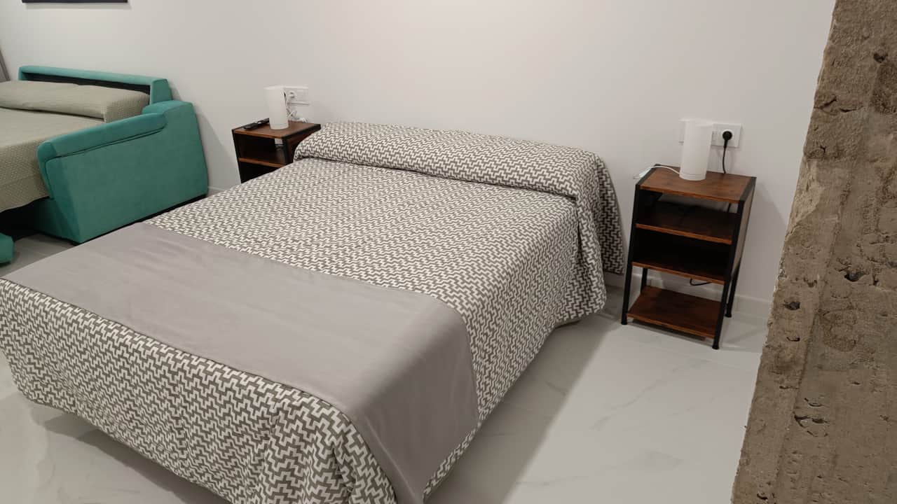 Detalle de la cama principal y sofá cama en el dormitorio