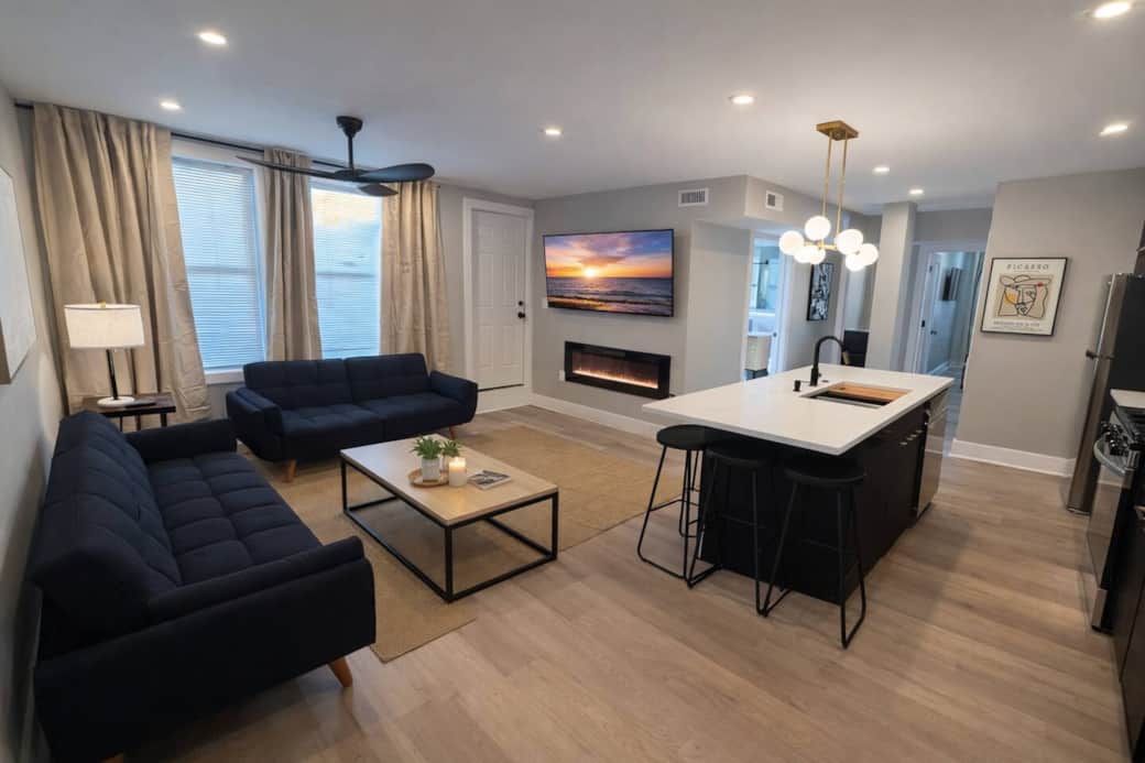spacious living room! It features 2 futon sofa beds, perfect for accommodating extra guests. Enjoy your favorite shows on the 50-inch TV,  Cozy up by the fireplace underneath for a warm atmosphere. There’s a door that leads to a small balcony outside