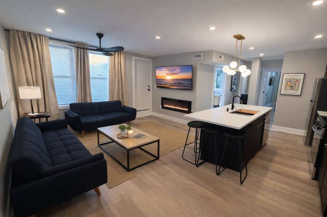 spacious living room! It features 2 futon sofa beds, perfect for accommodating extra guests. Enjoy your favorite shows on the 50-inch TV,  Cozy up by the fireplace underneath for a warm atmosphere. There’s a door that leads to a small balcony outside