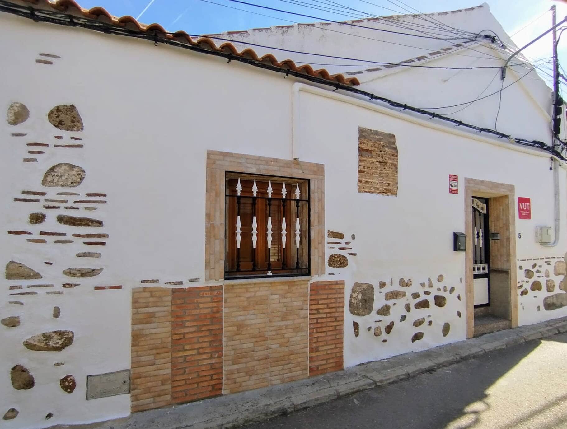 La Casita de Ale - Alojamiento rural en Polán, Toledo Fachada de La Casita de Ale con paredes blancas, detalles en piedra y señal VUT visible sobre la puerta