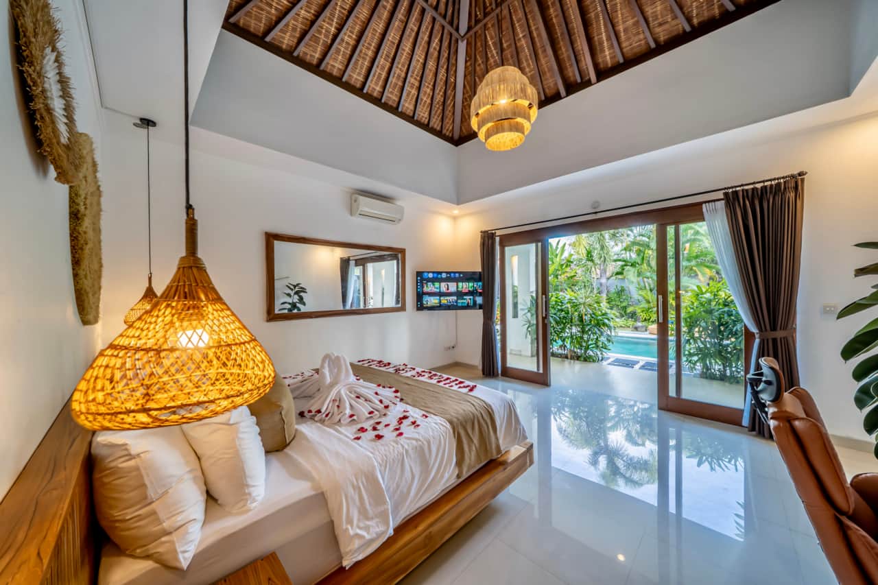 A bright bedroom with air conditioning and sliding doors overlooking the tropical garden.