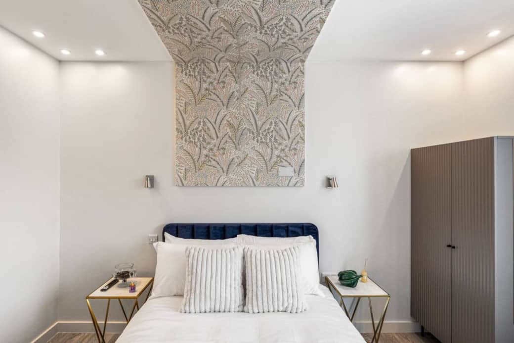 Bright and stylish bedroom featuring a plush double bed with luxury linens, feature wallpaper Bright and stylish bedroom featuring a plush double bed with luxury linens, feature wallpaper