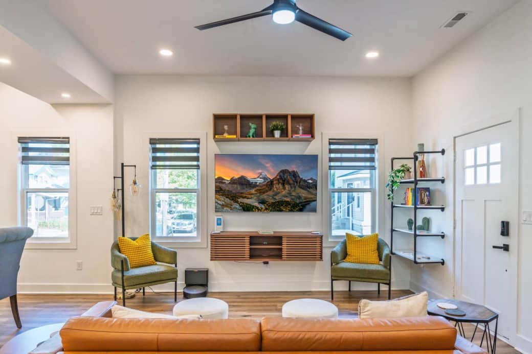 Open concept living room with 65" television and lots of windows with customizable roller shades.