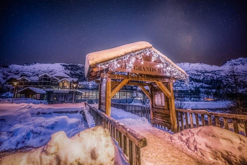 Entrée des Grands Bains du Monêtier illuminée la nuit sous un ciel étoilé, Serre Chevalier Vallée