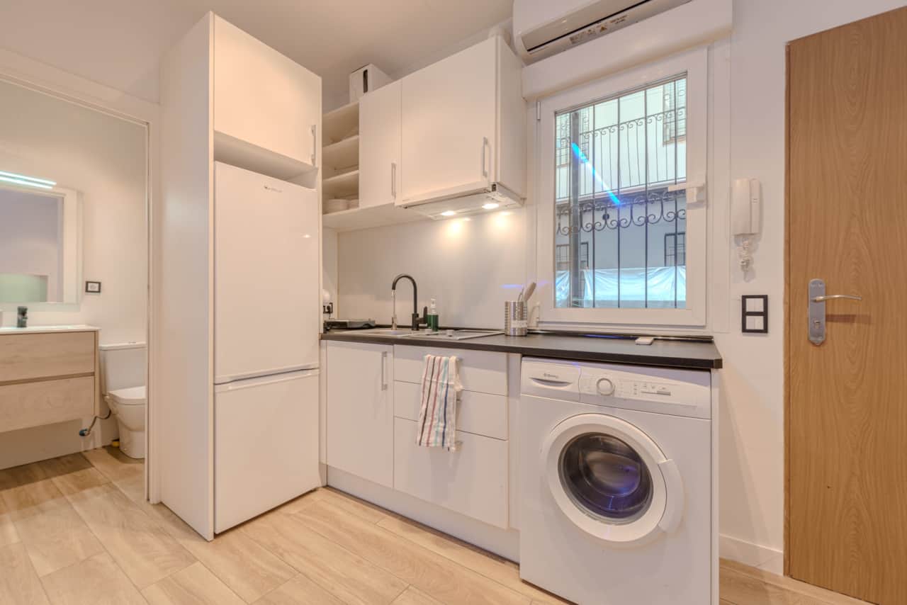 Cocina equipada con nevera alta, lavadora, vitrocerámica y ventana