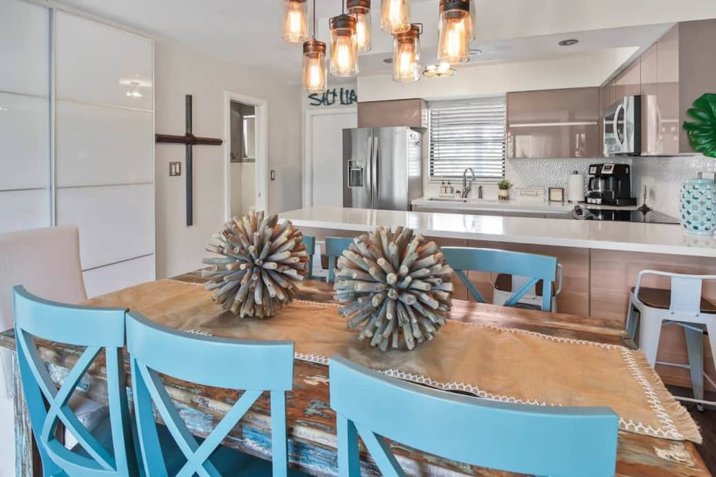 A unique blend of coastal and vintage—this living and dining area showcases a reclaimed wood door as a striking focal point.