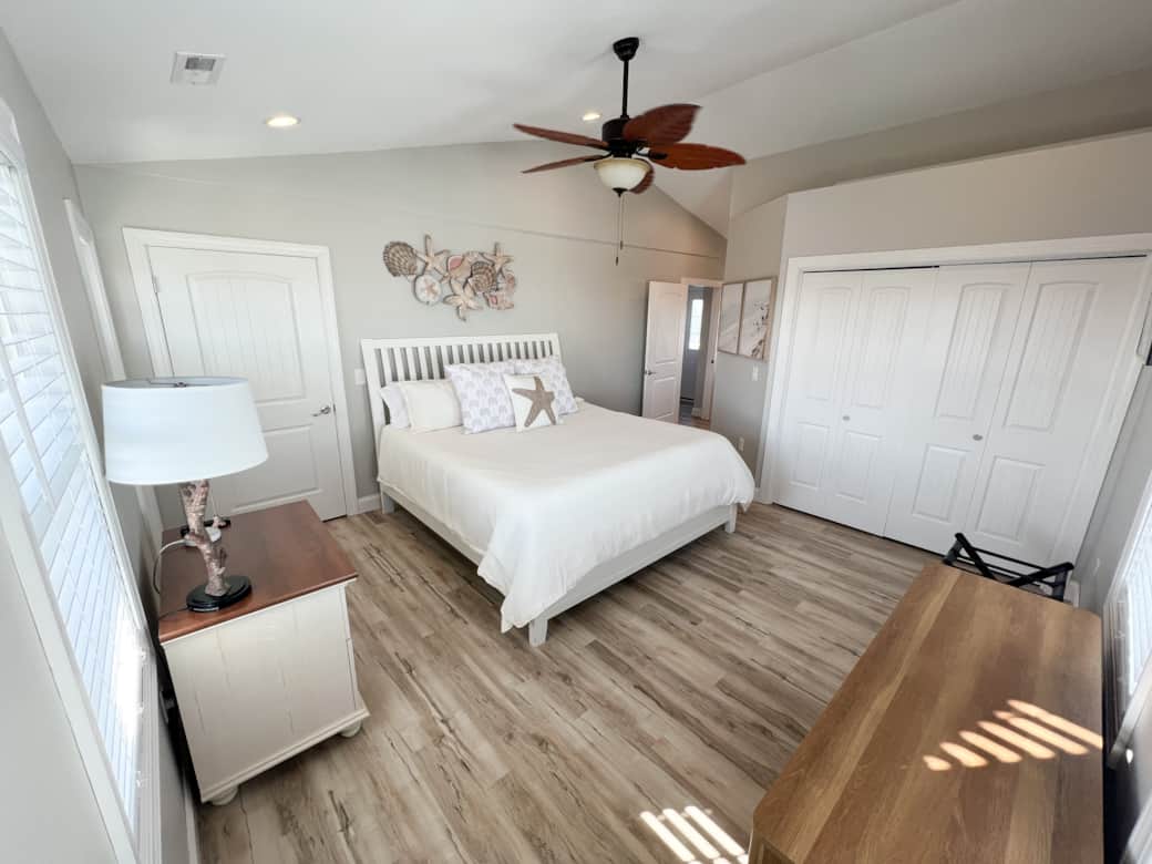 Corner ocean view primary bedroom with king bed, 2 chairs, large closet and attached bathroom