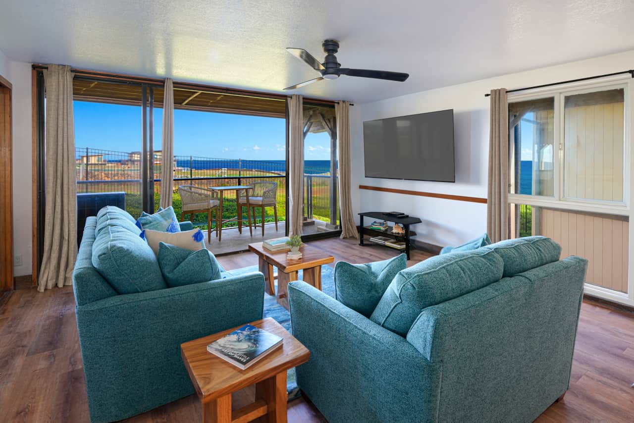 Bright living room with comfortable seating, large TV, and ocean views just beyond the lanai.