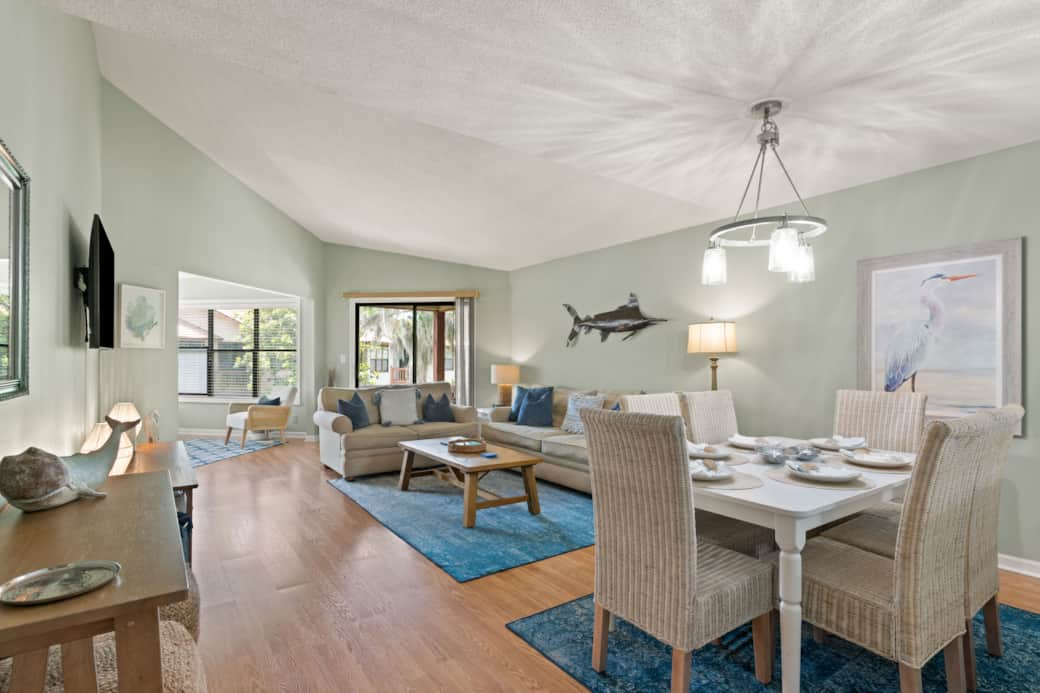 View of the Great Room, from the front Foyer, showing the dining table, Great Room, and balcony. 