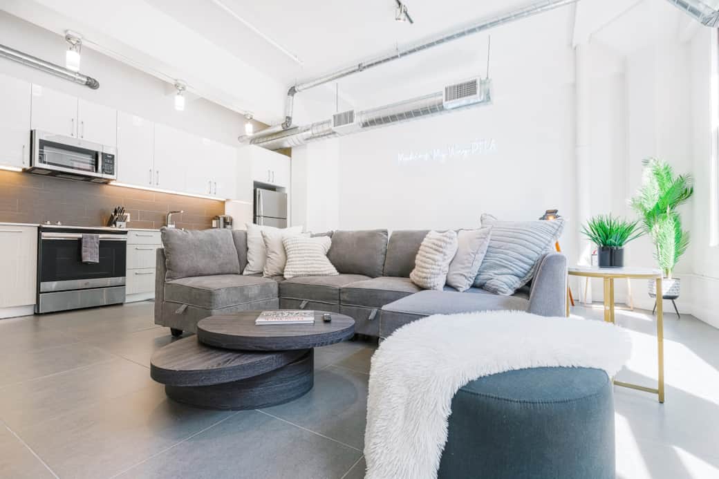 Airy living room with natural light, cozy seating, and a large TV for relaxing. Airy living room with natural light, cozy seating, and a large TV for relaxing.