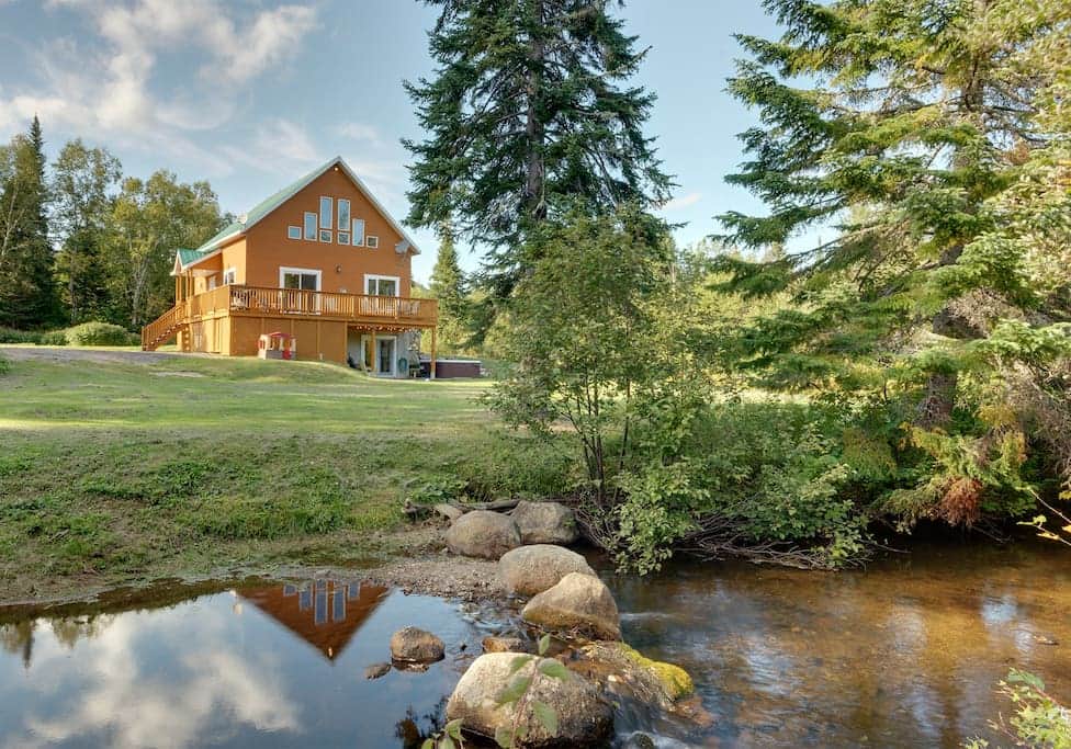Vue extérieure du chalet, de la cour et de la rivière