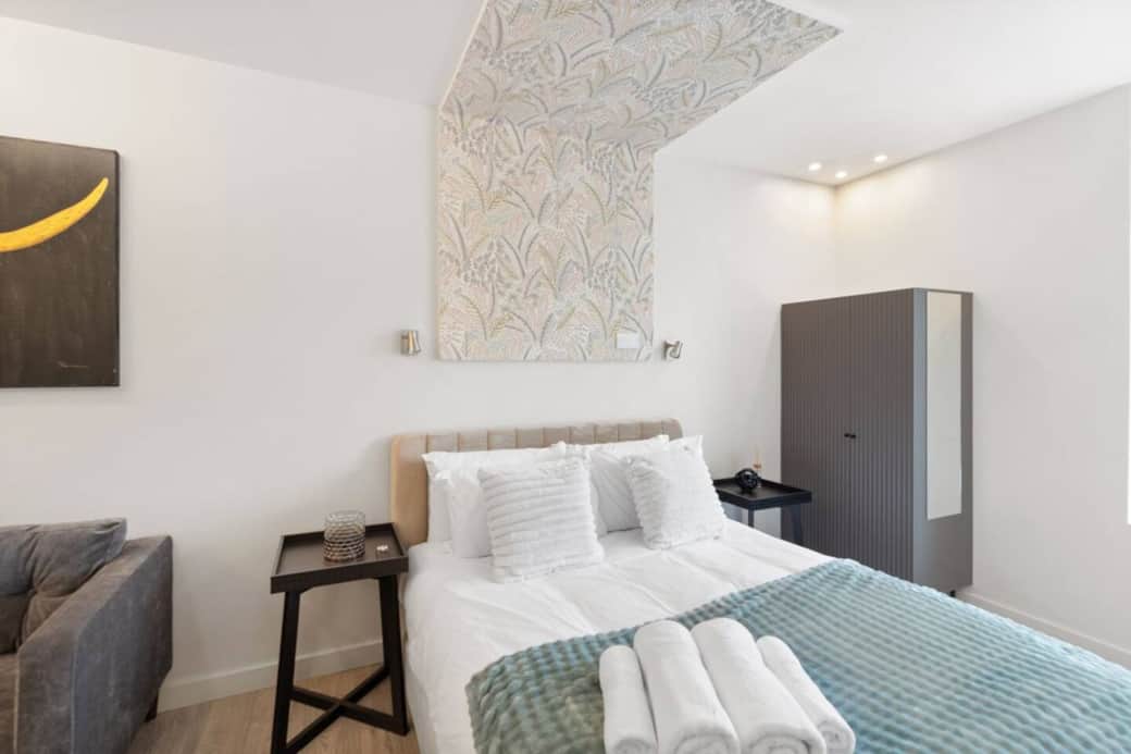 Bright and stylish bedroom featuring a plush double bed with luxury linens, feature wallpaper Bright and stylish bedroom featuring a plush double bed with luxury linens, feature wallpaper