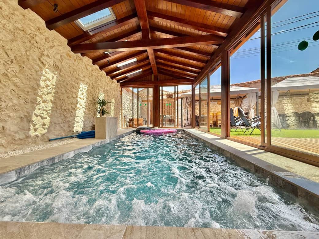 Piscina cubierta y climatizada, rodeada de paredes de piedra y techos de madera. Con grandes ventanales al patio, permite disfrutar del baño en cualquier época del año en un entorno único.