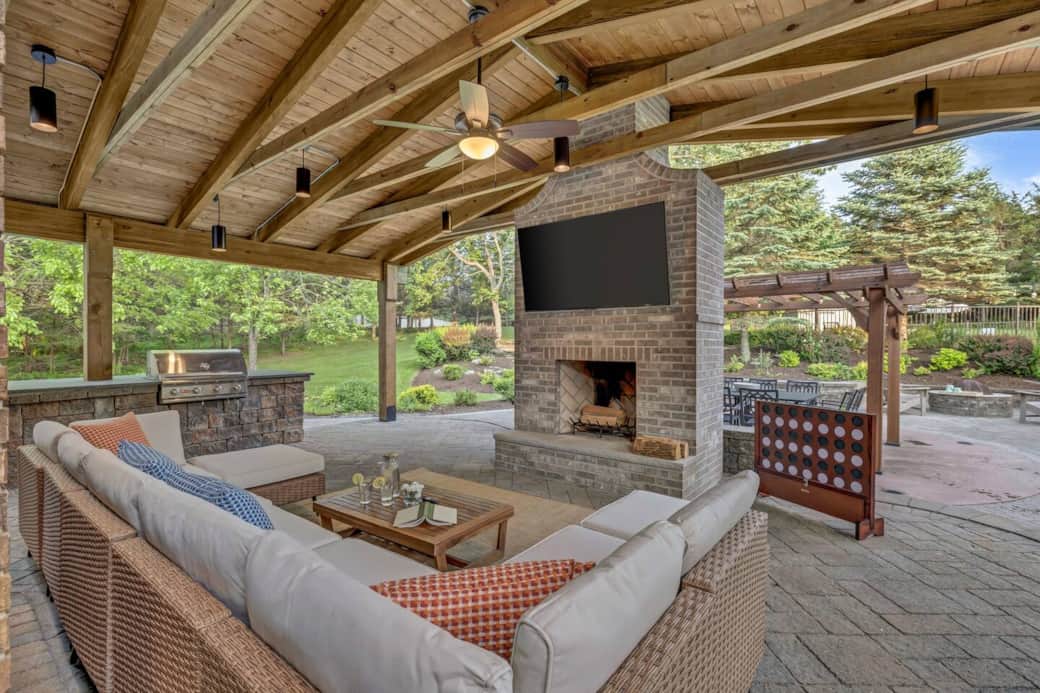 Experience the ultimate four-season hangout. An elegantly covered outdoor living area with a wood-burning fireplace, chef’s grill and kitchen, 65” TV, stylish lounge furniture, and games for all ages. 
