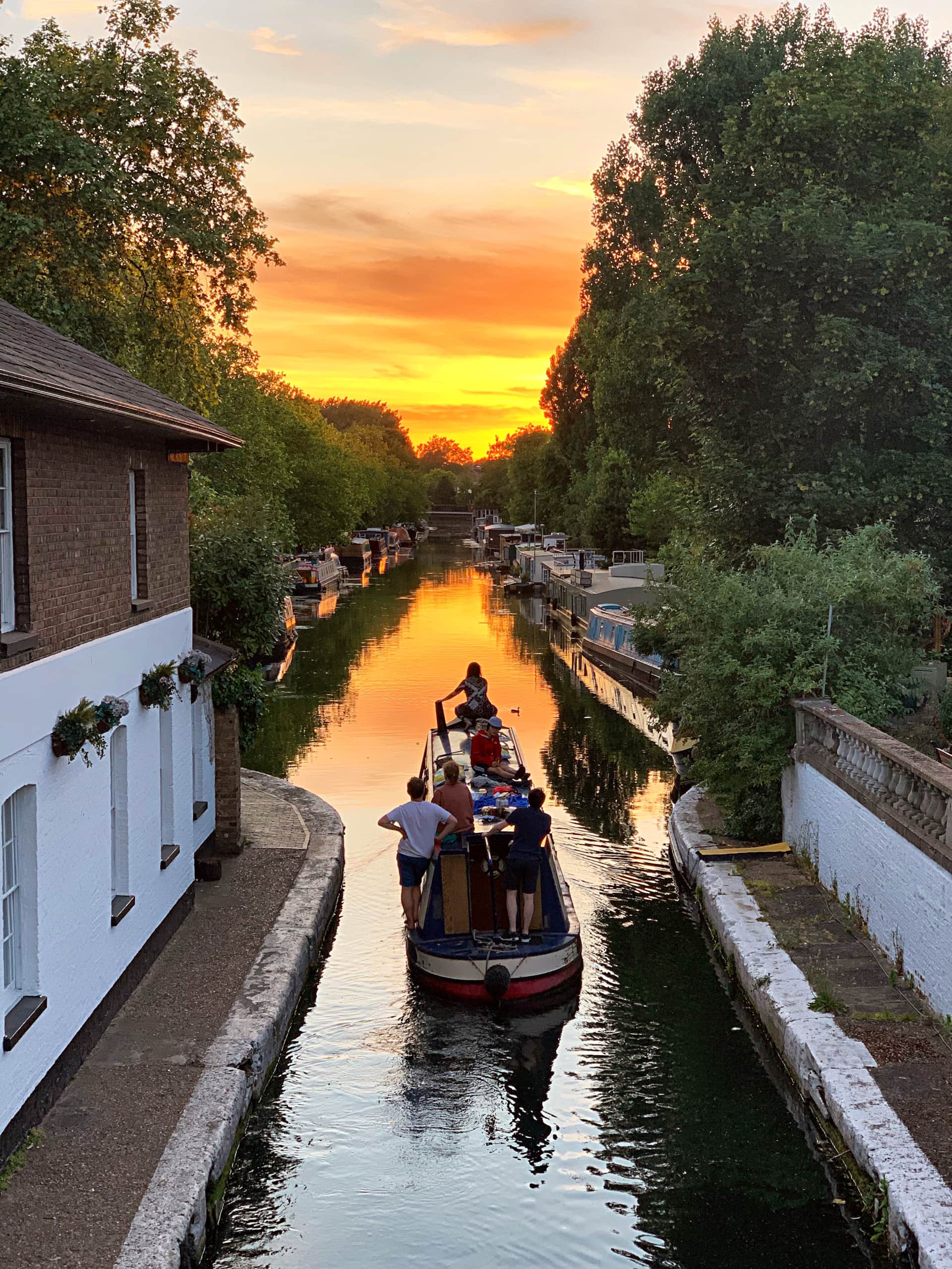 Family on a narrowboat holiday driving towards the sunset