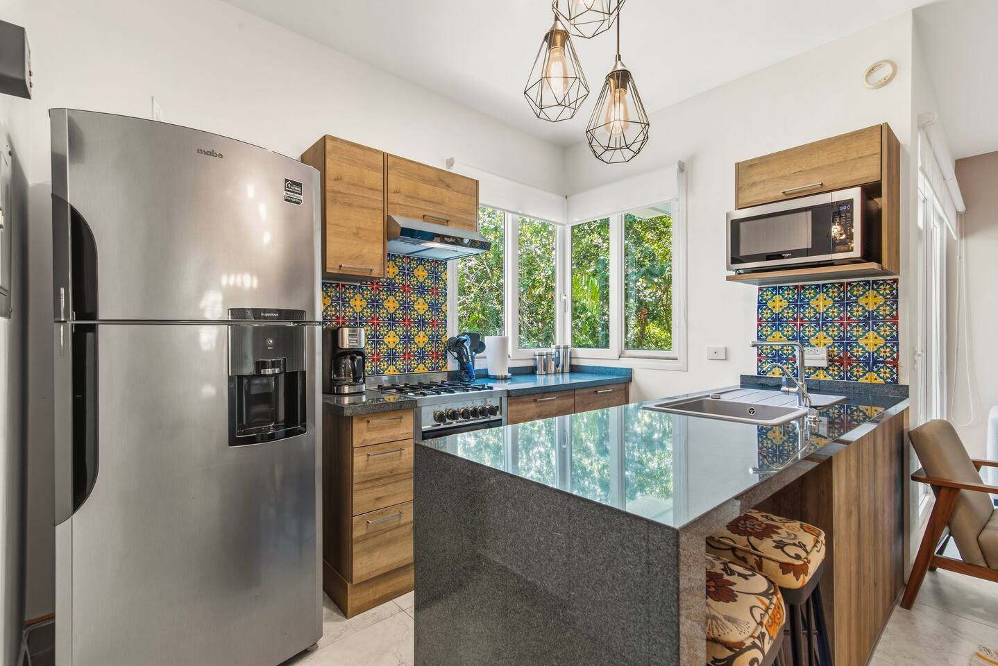 Cocine en la cocina totalmente equipada con estufa de 4 quemadores, horno, microondas, refrigerador, licuadora, tostadora, especias y cubiertos. Disfrute de agua filtrada, cafetera de goteo con café incluido, barra de desayuno con asientos para 3 y persianas opacas.