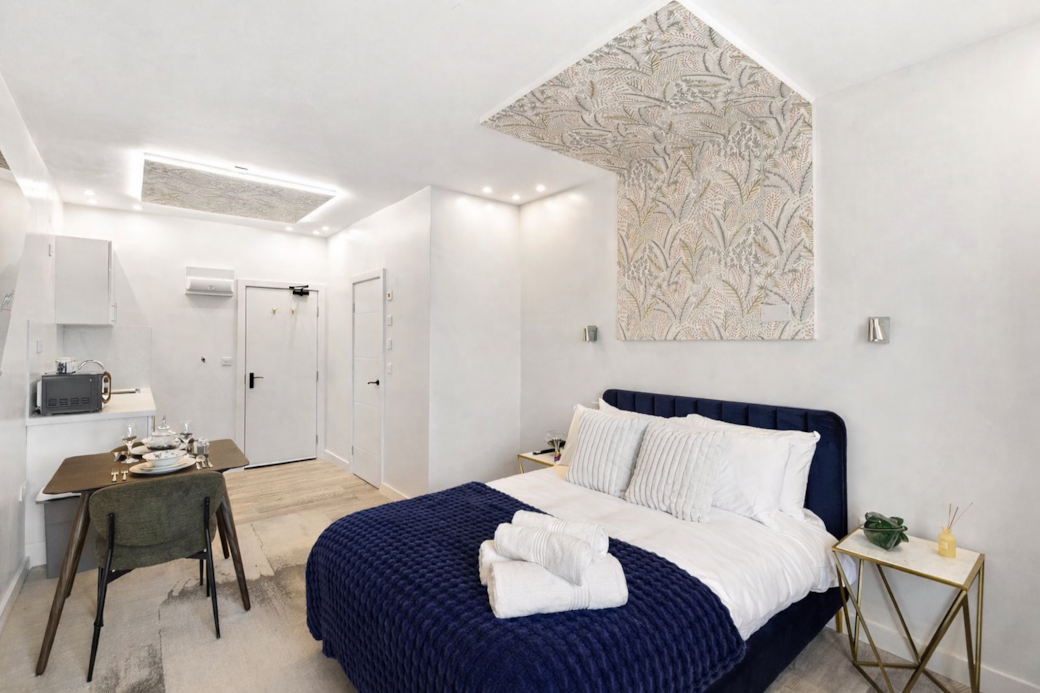 Bright and stylish bedroom featuring a plush double bed with luxury linens, feature wallpaper Bright and stylish bedroom featuring a plush double bed with luxury linens, feature wallpaper