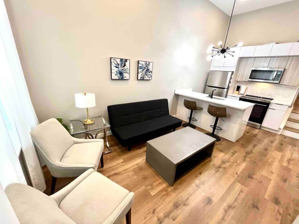 This living room boasts a flat screen tv with an impressive selection of Ruko channels. Accompanied by a comfortable futon sofa bed, two elegant living room chairs, and a generous window that graciously allows natural light to illuminate the space.
