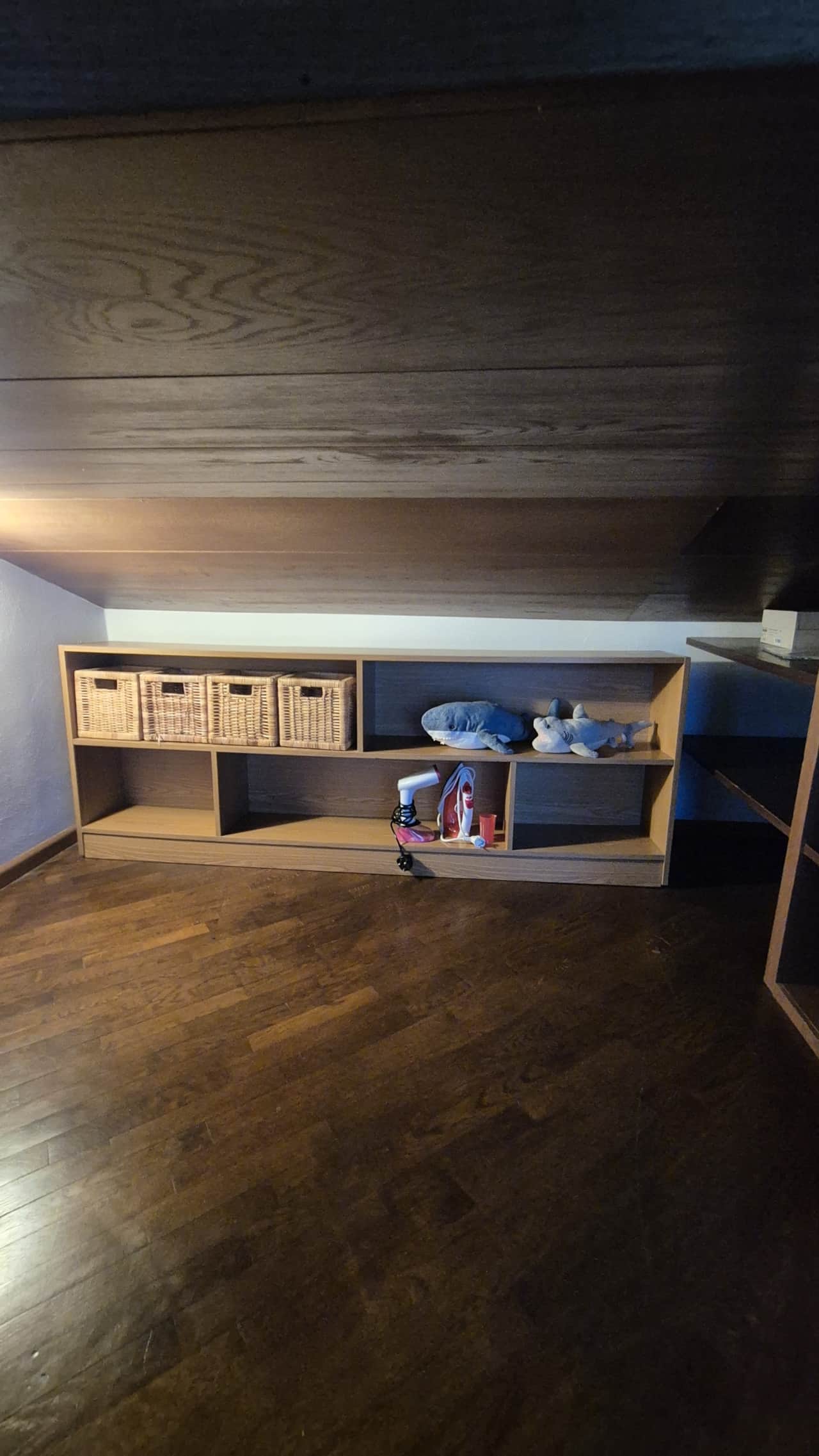 Dormitorio con cama y estantes de pared bajo el techo de madera
