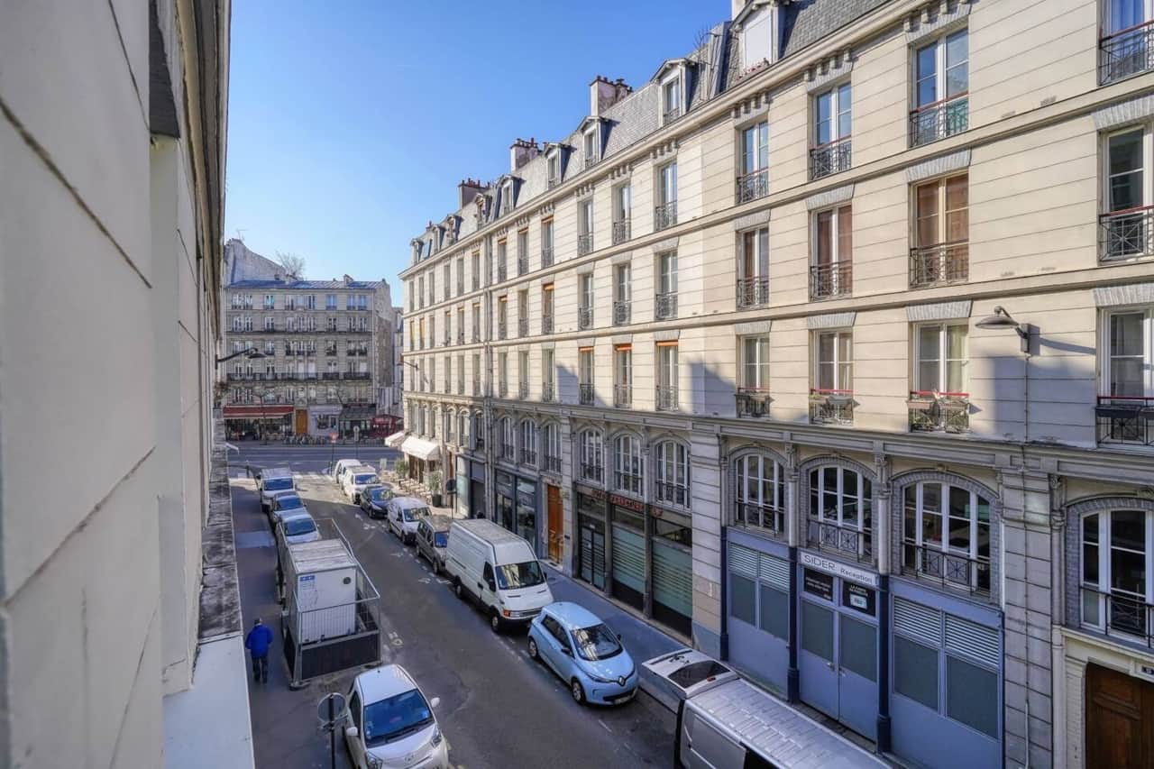 Vue pittoresque sur une rue parisienne typique, avec des bâtiments haussmanniens et une circulation animée, capturant l'essence de la vie urbaine à Paris.