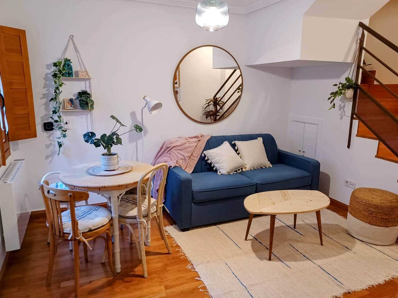 Salón con sofá azul, comedor redondo y escalera