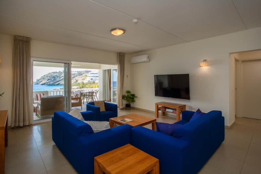 The living room has an airconditioner, a large TV with live channels and comfortable furniture.